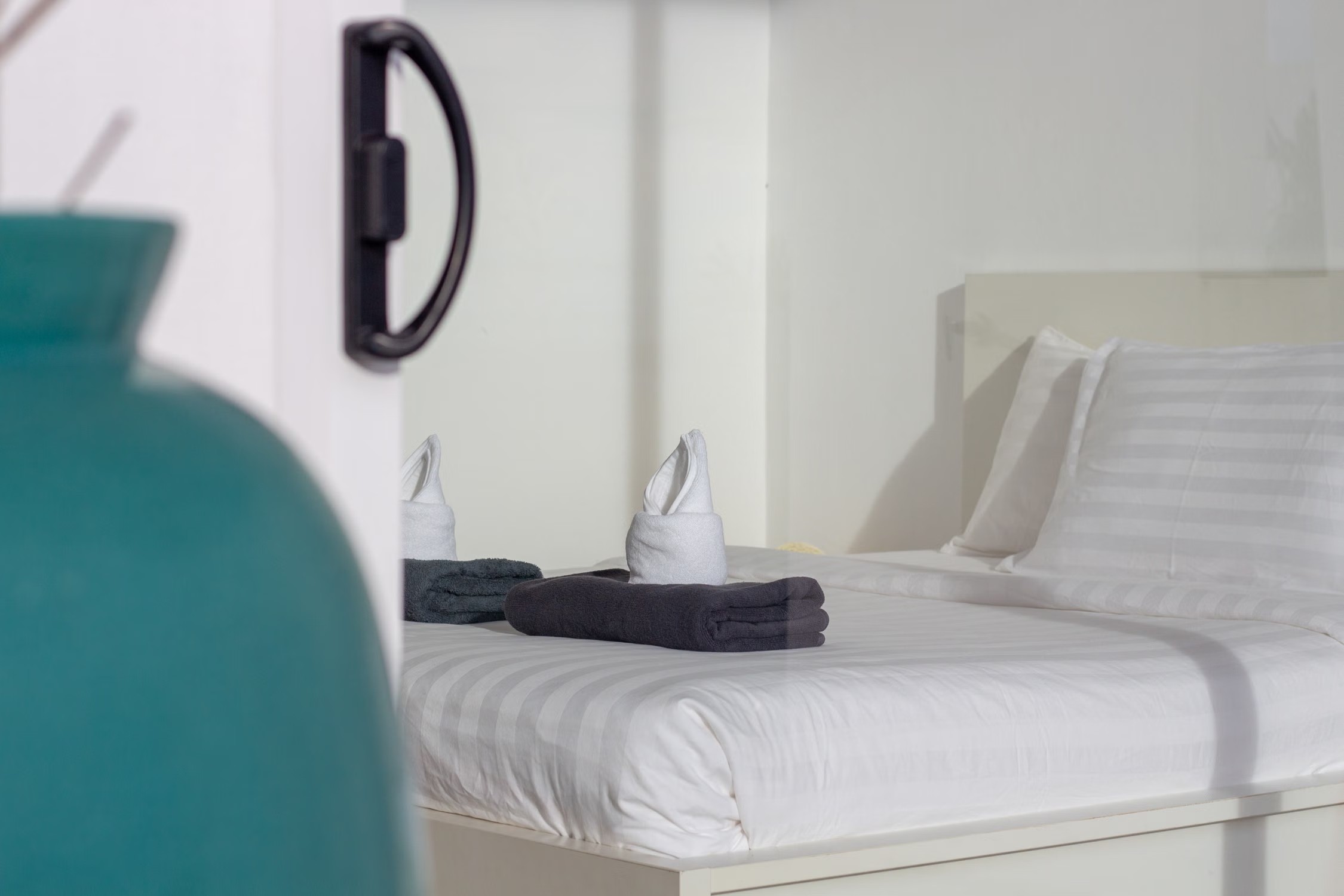 Stock photo of a guest bed with white bedding and folded towels.
