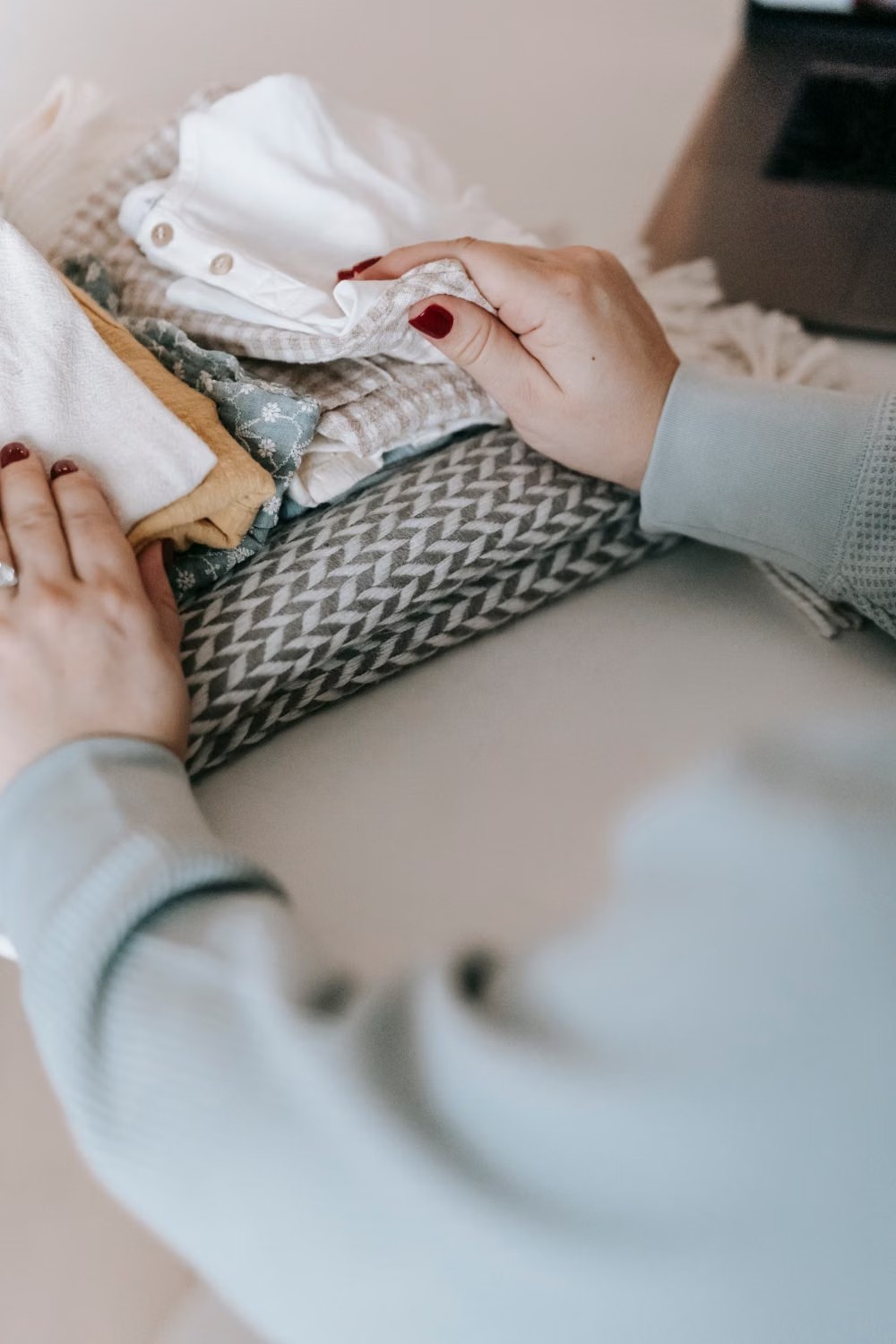 Stock photo of hands organizing a small pile of family clothing.