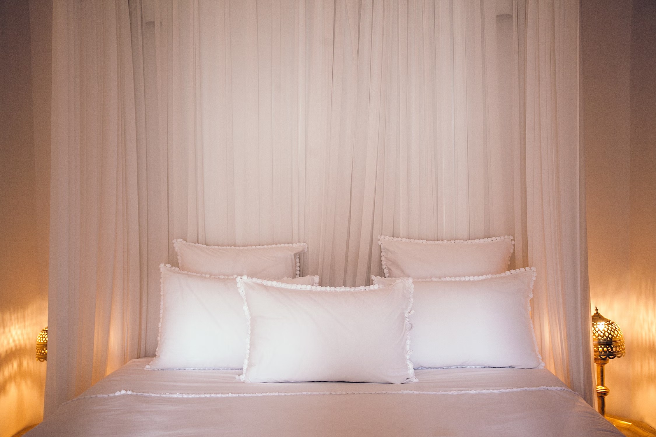 Stock photo of a guest bed with pillows and light colored bedding.